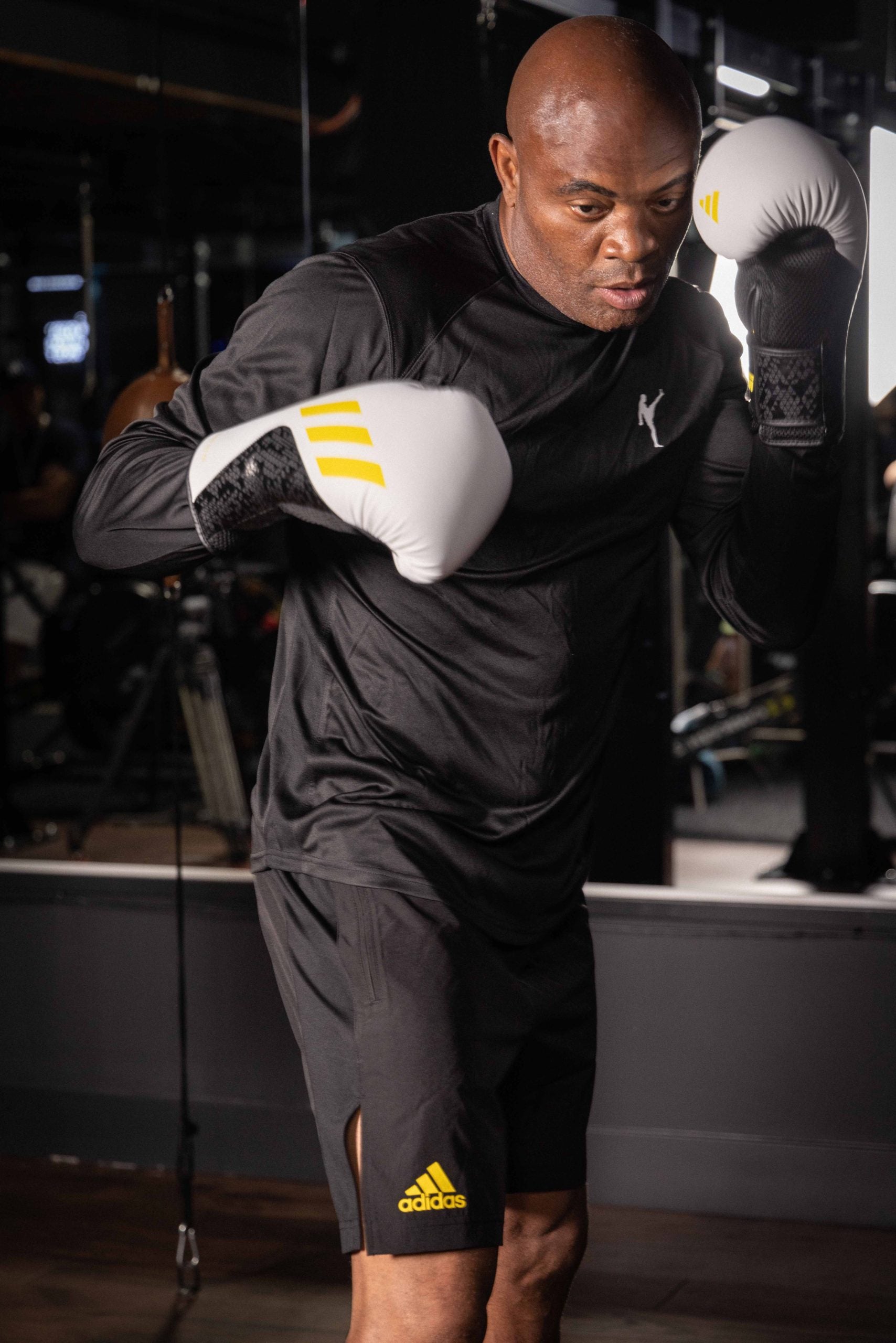 Man wearing boxing gloves in Adidas training shorts.