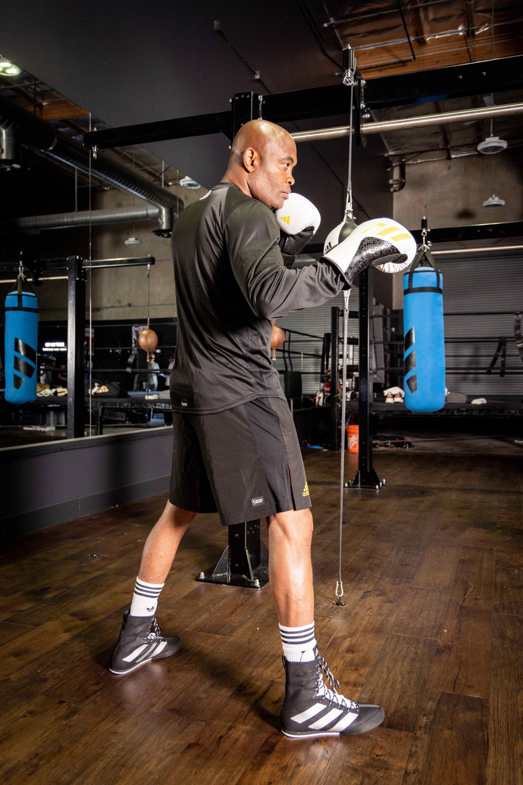 A man in a gym wearing boxing gloves.