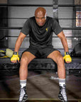 A man sitting on a bench in a black XL half sleeve T-shirt.