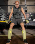 Man in boxing gloves and shorts sitting on bench.