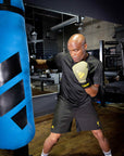 A man wearing boxing gloves and punching bag.